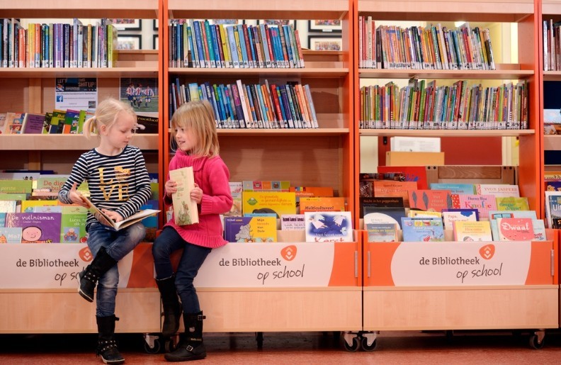 Twee meisjes voor de boekenkast van de Bibliotheek op school