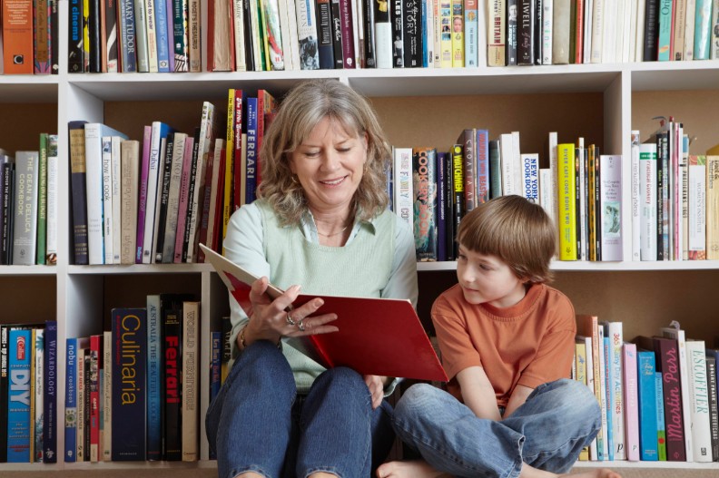 Kind en vrouw lezen een boek bij een boekenkast